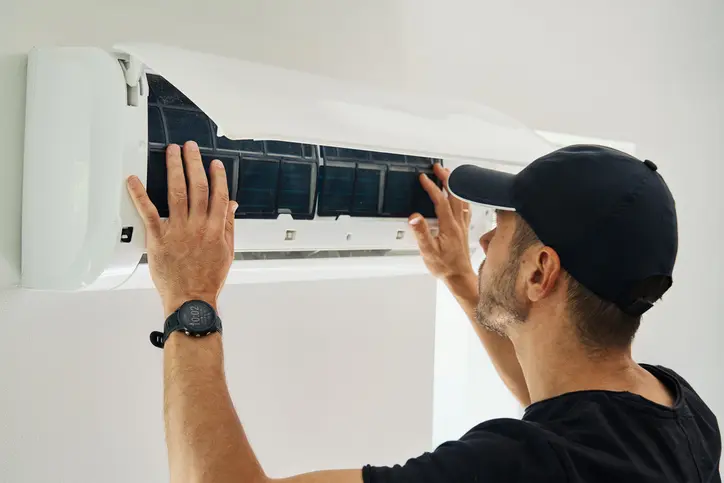 Air Conditioner Maintenance. Male Technician Repairs Home Climate System In Living Room